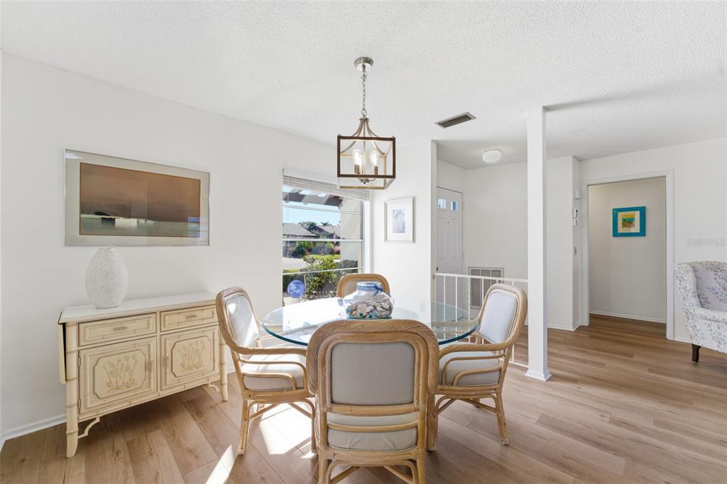 A dining area features a glass-topped table, rattan chairs, a sideboard, and light wood flooring — 605 APPLE LANE, ENGLEWOOD, FL