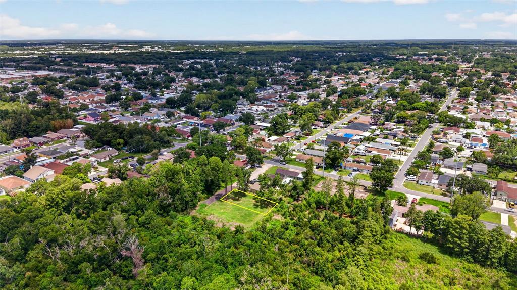An aerial view shows a vacant, rectangular lot outlined in yellow amidst a suburban neighborhood — 6817 N BLOSSOM AVENUE, TAMPA, FL