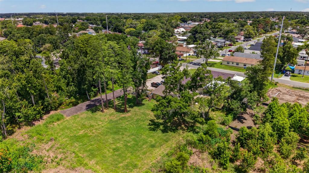 An aerial view shows a grassy lot with scattered trees next to a residential street — 6817 N BLOSSOM AVENUE, TAMPA, FL