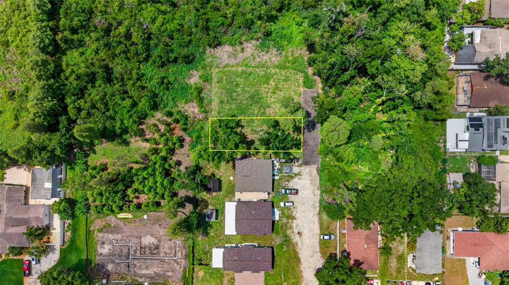 An aerial view shows a rectangular lot highlighted in yellow amidst surrounding residential properties — 6817 N BLOSSOM AVENUE, TAMPA, FL