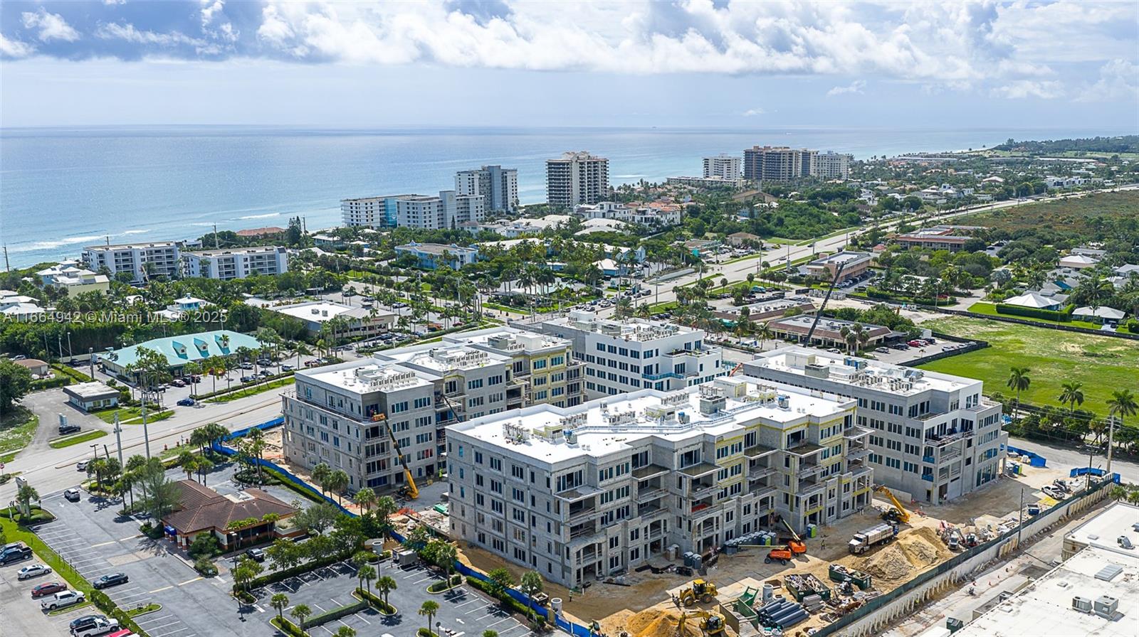 An aerial view shows a large multi-story apartment complex under construction near the ocean — 1011 US Highway One # A202, Juno Beach FL 33408, JUNO BEACH, FL