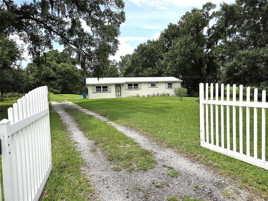 A one-story house with a white exterior sits behind a white picket fence and driveway — 1214 JERRY SMITH ROAD, DOVER, FL