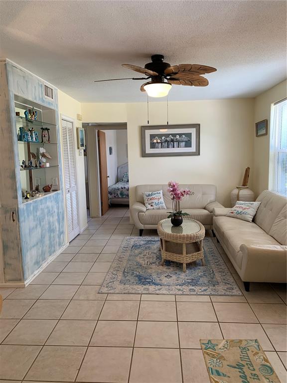 A living room with tile floors, two white sofas, a wicker coffee table, and shelving — 1935 S CENTRAL AVENUE, FLAGLER BEACH, FL