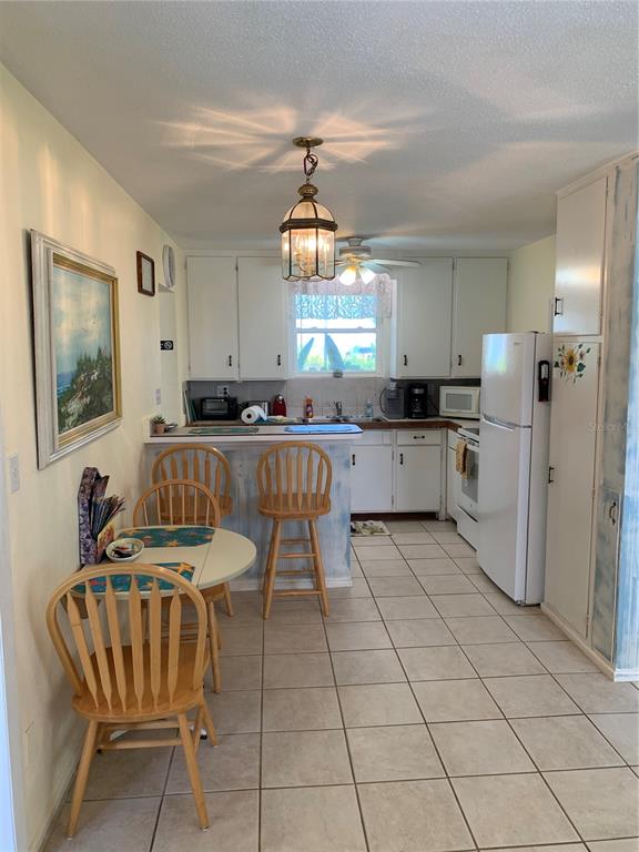 A kitchen features white cabinets, tile flooring, a breakfast bar, and a small dining table — 1935 S CENTRAL AVENUE, FLAGLER BEACH, FL