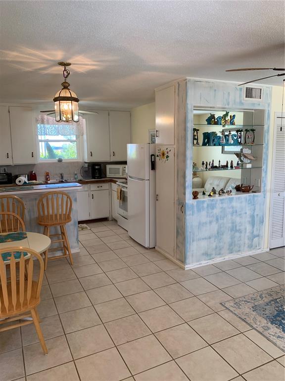 A kitchen with white cabinets, tile flooring, and a decorative pass-through display shelf — 1935 S CENTRAL AVENUE, FLAGLER BEACH, FL