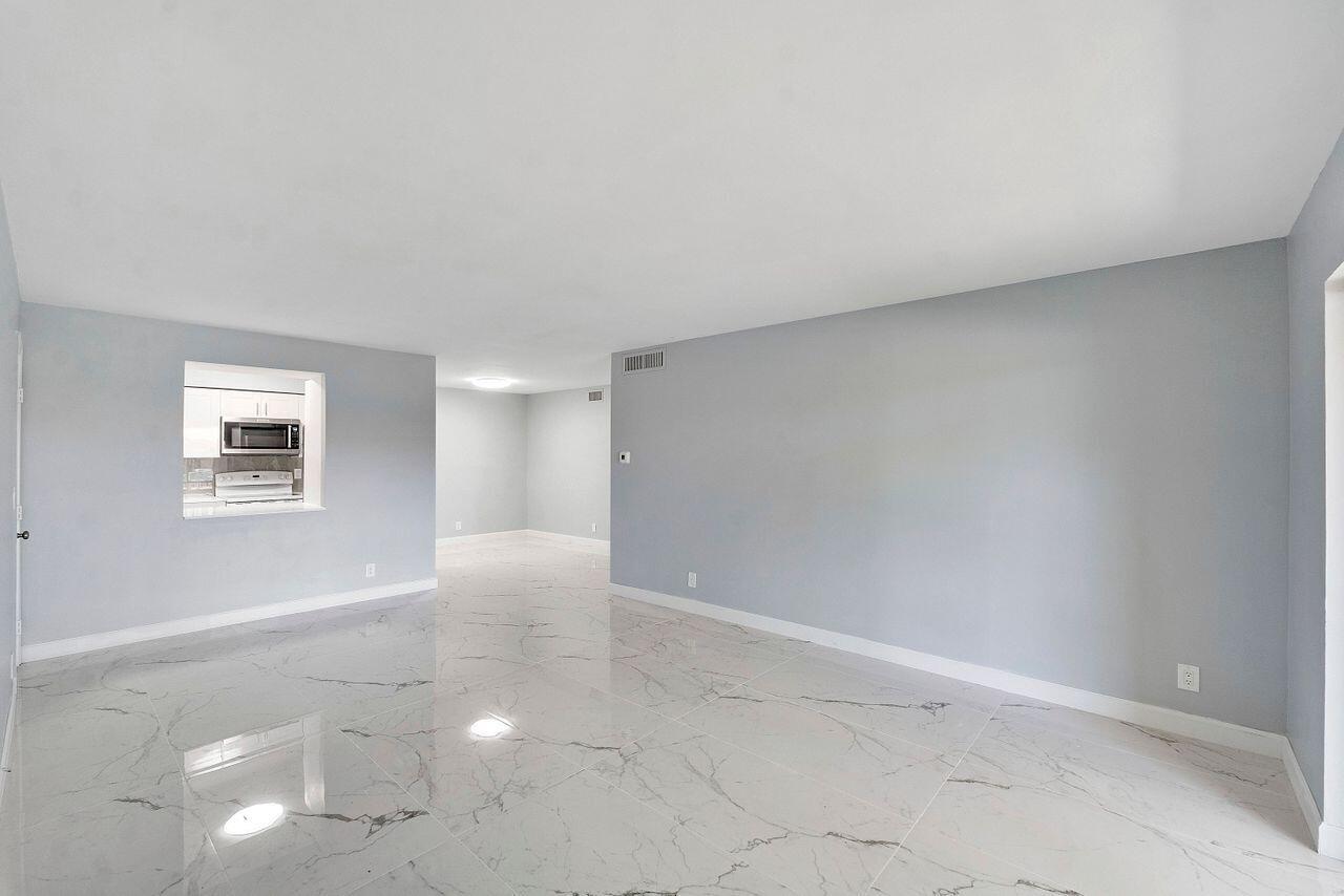 An empty room with light gray walls and white marble-patterned tile flooring — 9960 Pineapple Tree Drive # 107, Boynton Beach FL 33436, BOYNTON BEACH, FL