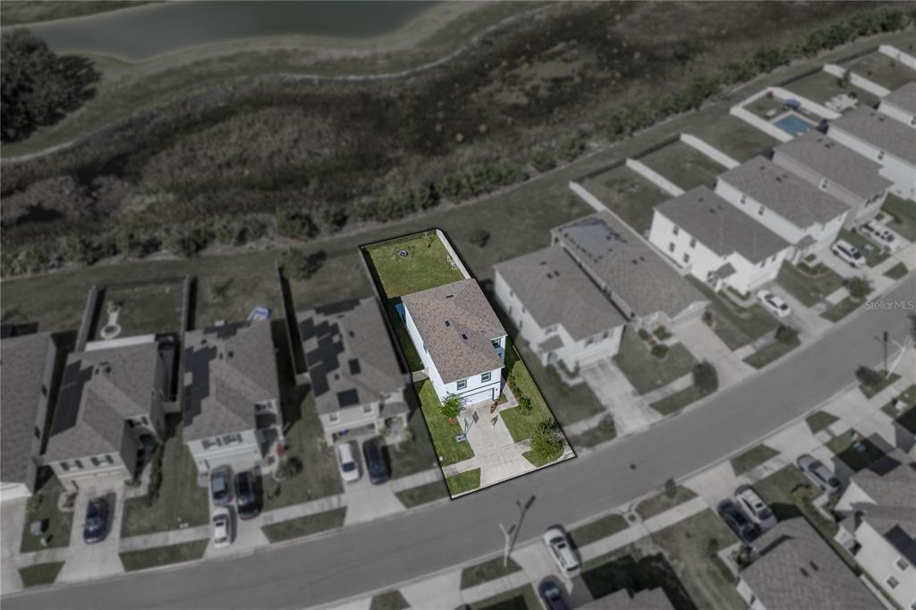 An aerial view shows a two-story house with a fenced backyard bordering a pond — 10951 PENNY GALE LOOP, SAN ANTONIO, FL