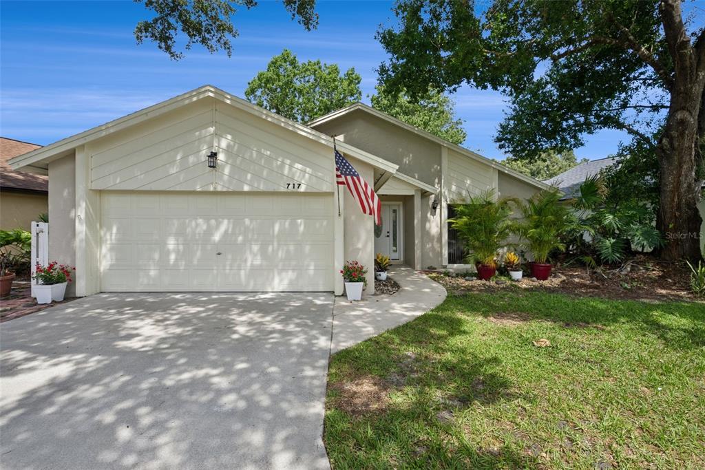 A single-story house with a beige exterior, a two-car garage, and an American flag — 717 ADIDAS ROAD, WINTER SPRINGS, FL