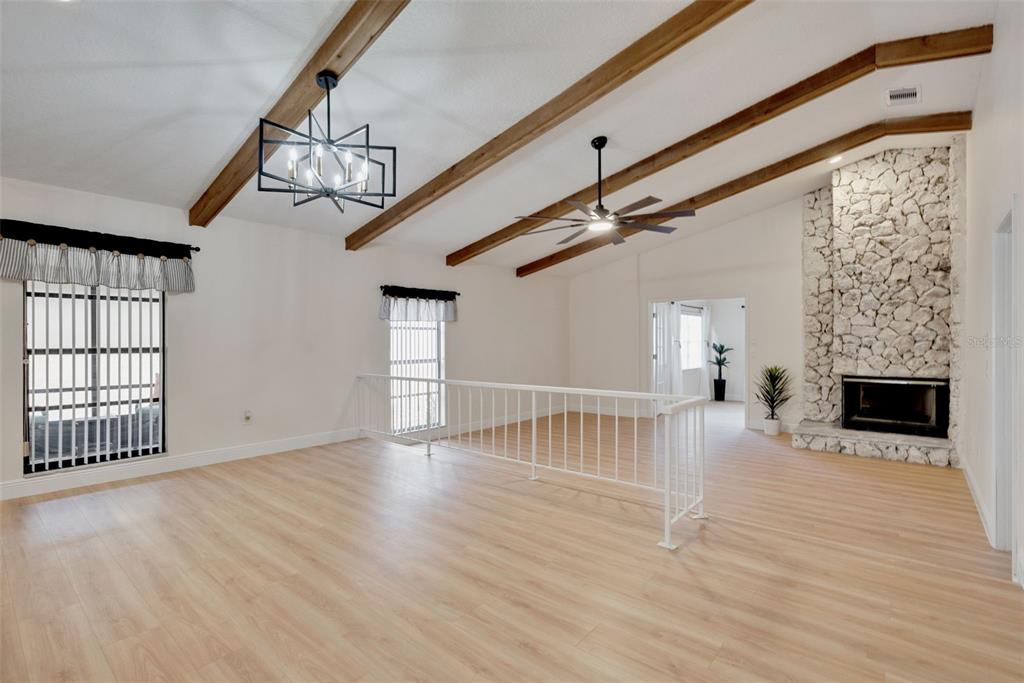 A living room features vaulted ceilings with exposed wood beams, light wood flooring, and stone fireplace — 717 ADIDAS ROAD, WINTER SPRINGS, FL