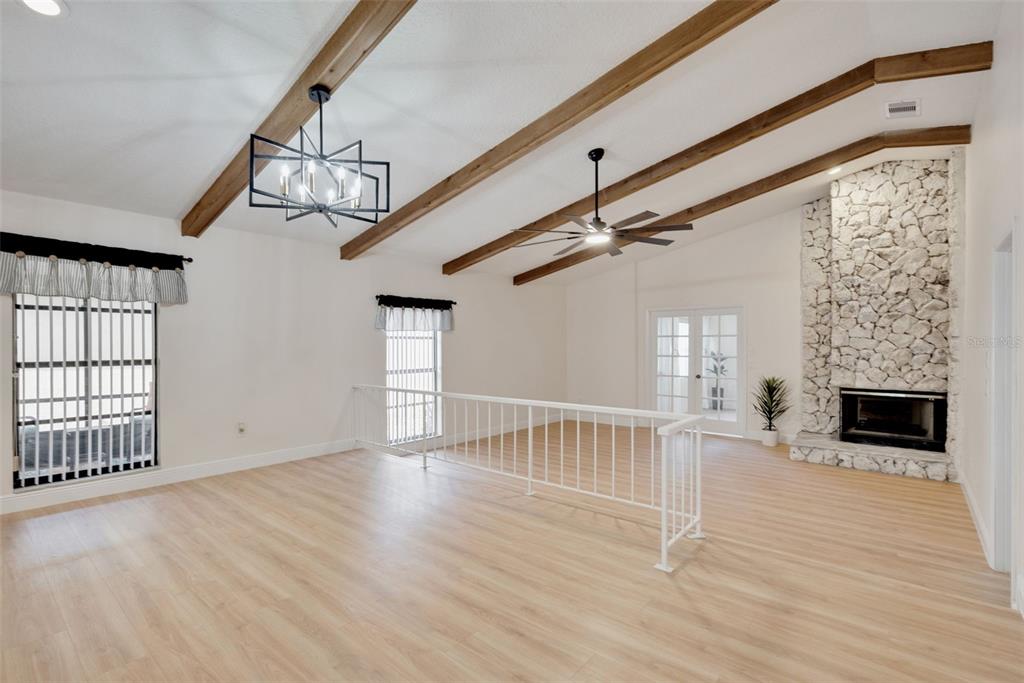 A living room features vaulted ceilings with wood beams, light wood flooring, and a stone fireplace — 717 ADIDAS ROAD, WINTER SPRINGS, FL