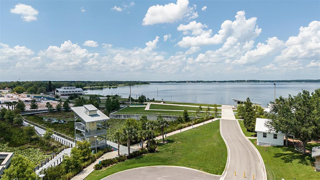 An aerial view shows a park with a lake, a tall observation tower, and paved paths — 208 STREAMWATER WAY, GROVELAND, FL