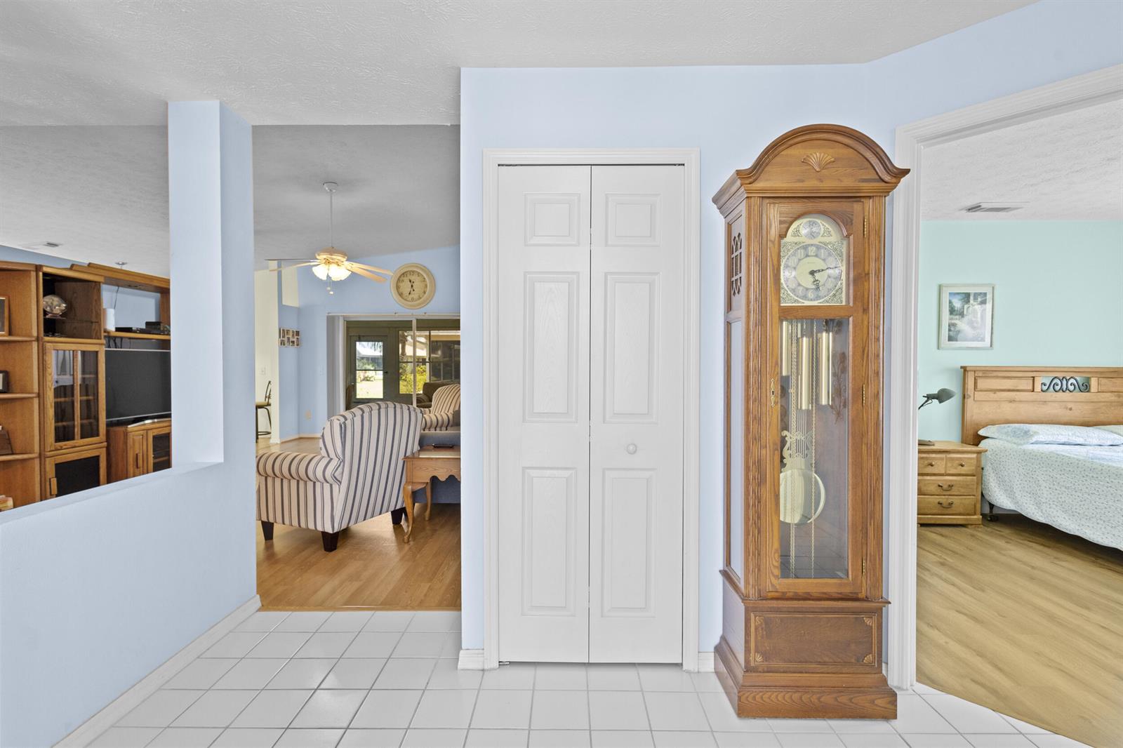 A hallway with white tile floors, a grandfather clock, and a closet between two rooms — 6527 Alheli, Fort Pierce FL 34951, FORT PIERCE, FL