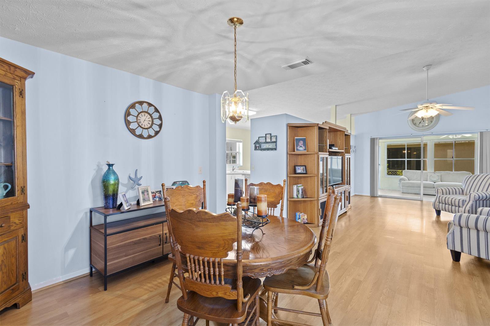 A dining area with a wooden table and chairs sits adjacent to a living room — 6527 Alheli, Fort Pierce FL 34951, FORT PIERCE, FL