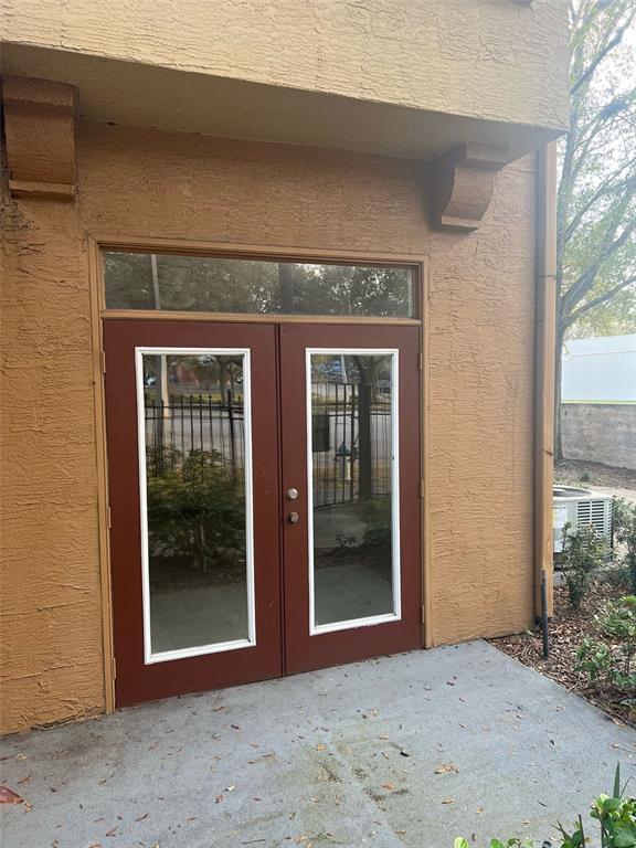 A set of double glass doors with a transom window sits on a concrete patio — 6368 RALEIGH STREET UNIT 1803, ORLANDO, FL