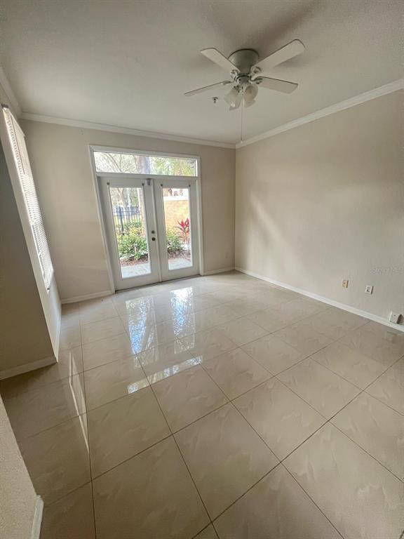 A room with light-colored tile flooring, a ceiling fan, and glass French doors leading outside — 6368 RALEIGH STREET UNIT 1803, ORLANDO, FL