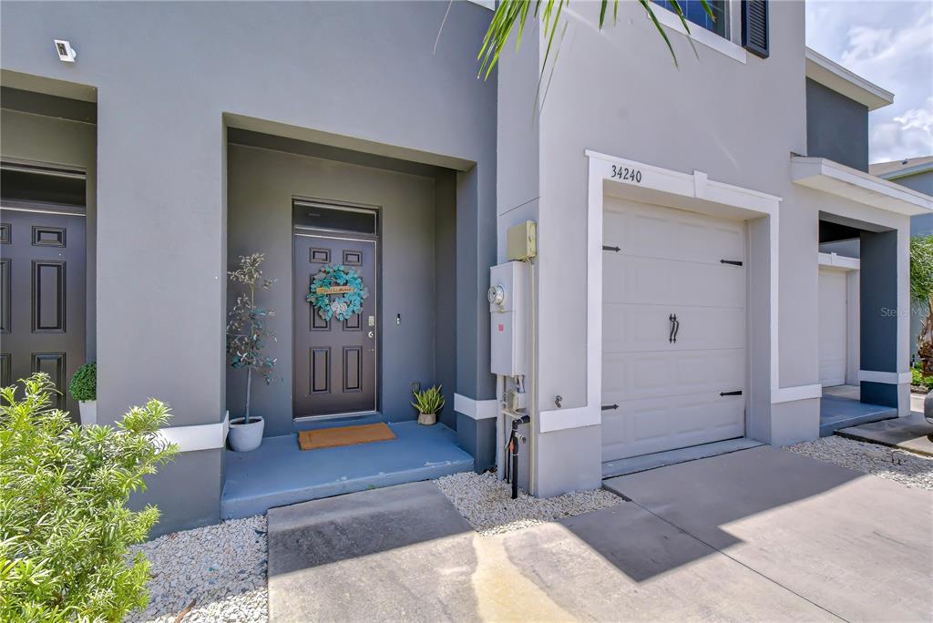The exterior of a modern townhouse features a gray facade, a garage, and a front entrance — 34240 REDWOOD DAWN LANE, WESLEY CHAPEL, FL