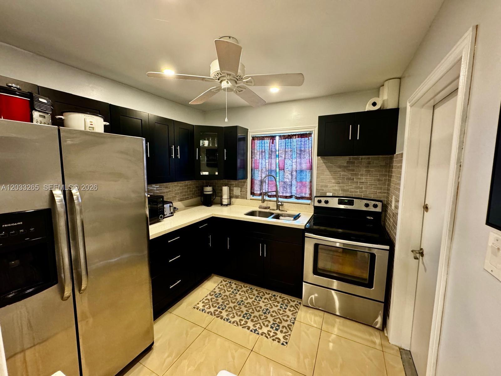 A kitchen features dark cabinets, stainless steel appliances, a tiled backsplash, and a ceiling fan — 5300 Washington St # H236, Hollywood FL 33021, HOLLYWOOD, FL