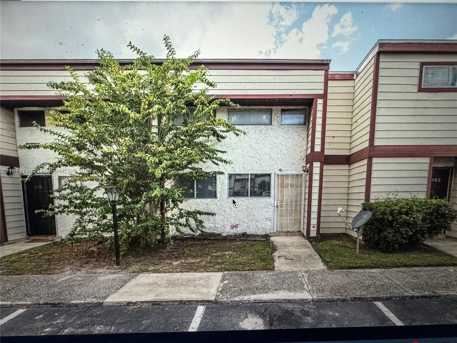 A two-story townhouse exterior features a white stucco facade, horizontal siding, and a large tree — 3984 Crayrich Circle # C5, Orlando FL 32839, ORLANDO, FL