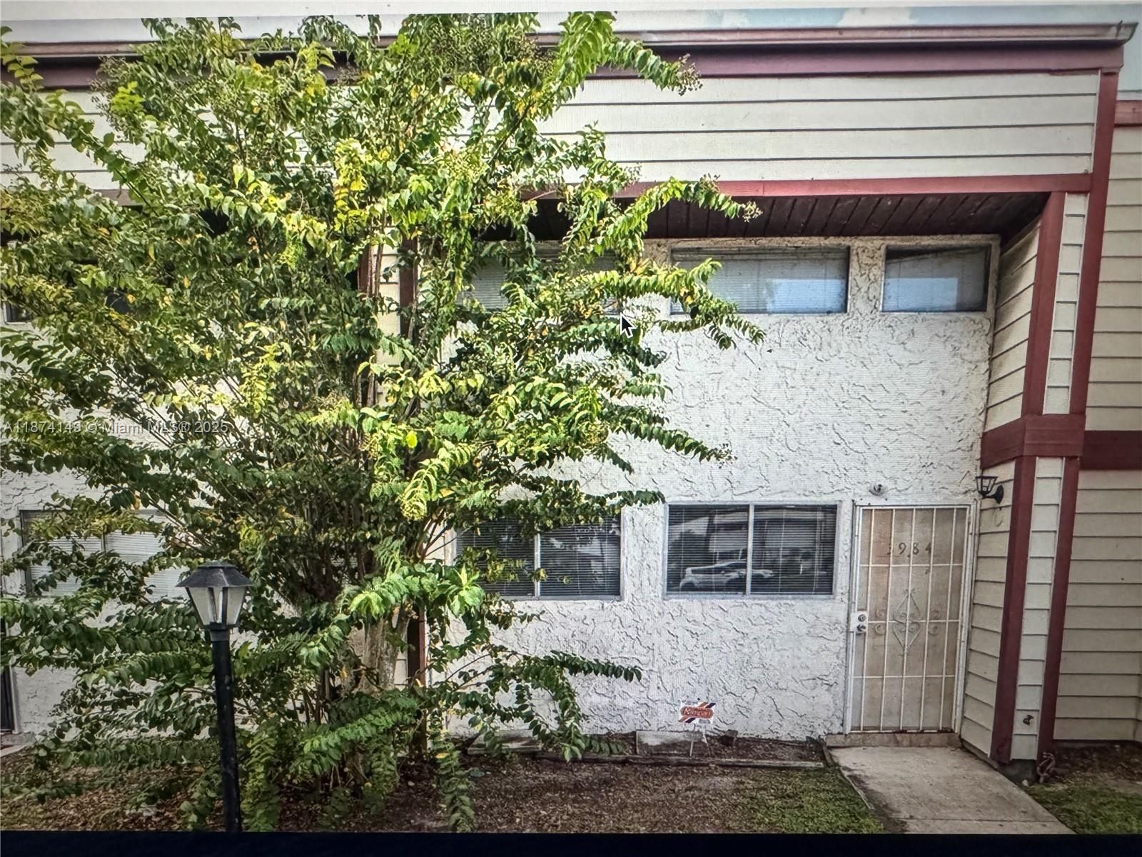 A two-story townhouse exterior features a white stucco facade, a large tree, and a metal door — 3984 Crayrich Circle # C5, Orlando FL 32839, ORLANDO, FL