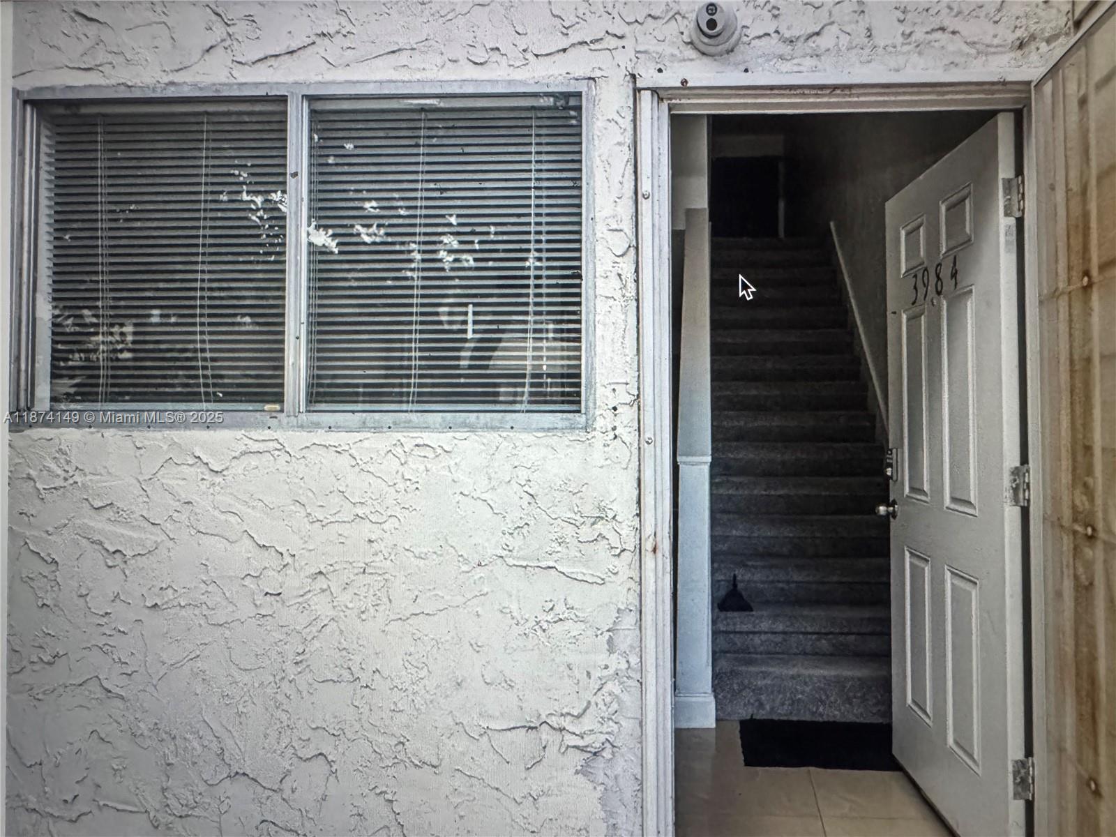 An open door reveals a carpeted staircase leading upward next to a window with blinds — 3984 Crayrich Circle # C5, Orlando FL 32839, ORLANDO, FL