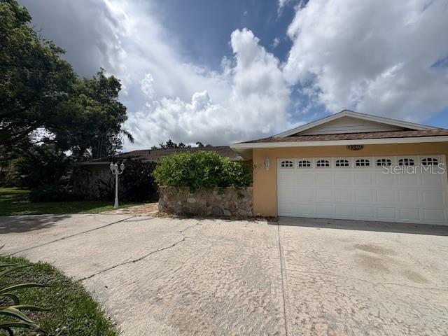A single-story house with a white garage door and a stone planter in the front yard — 4240 CHARING CROSS ROAD, SARASOTA, FL
