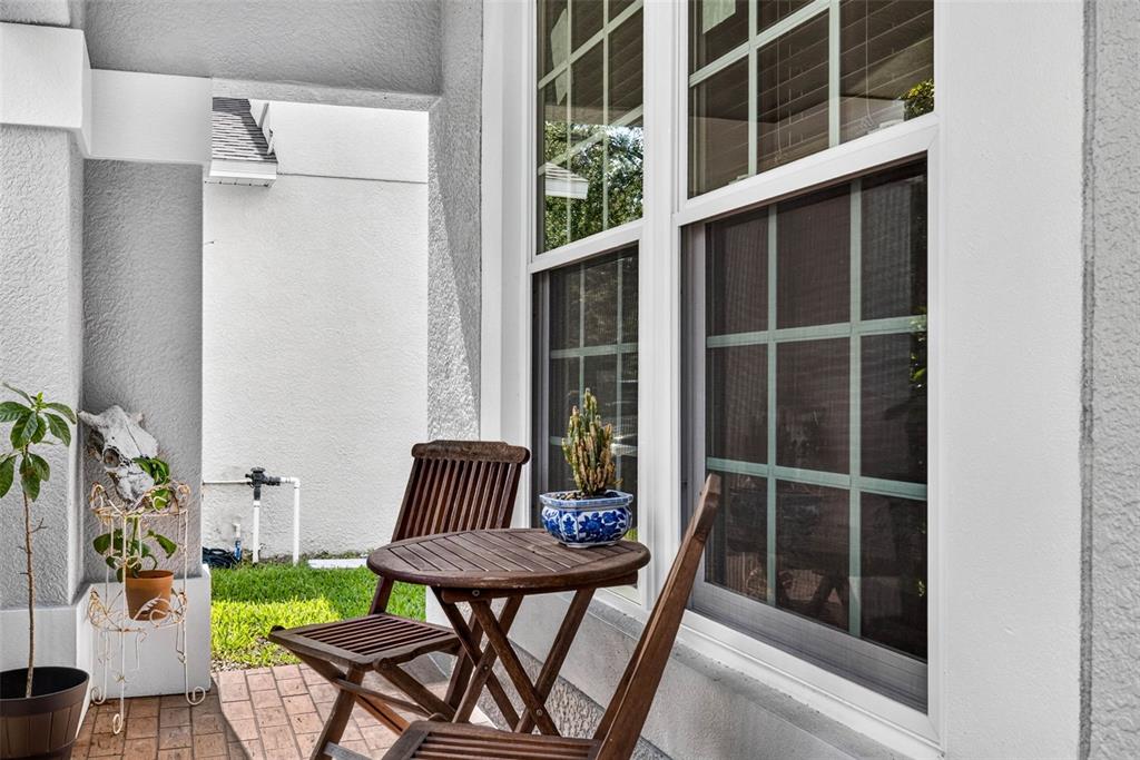 A small wooden table and two chairs sit on a brick patio beside a window — 11428 BLUE LILAC AVENUE, RIVERVIEW, FL