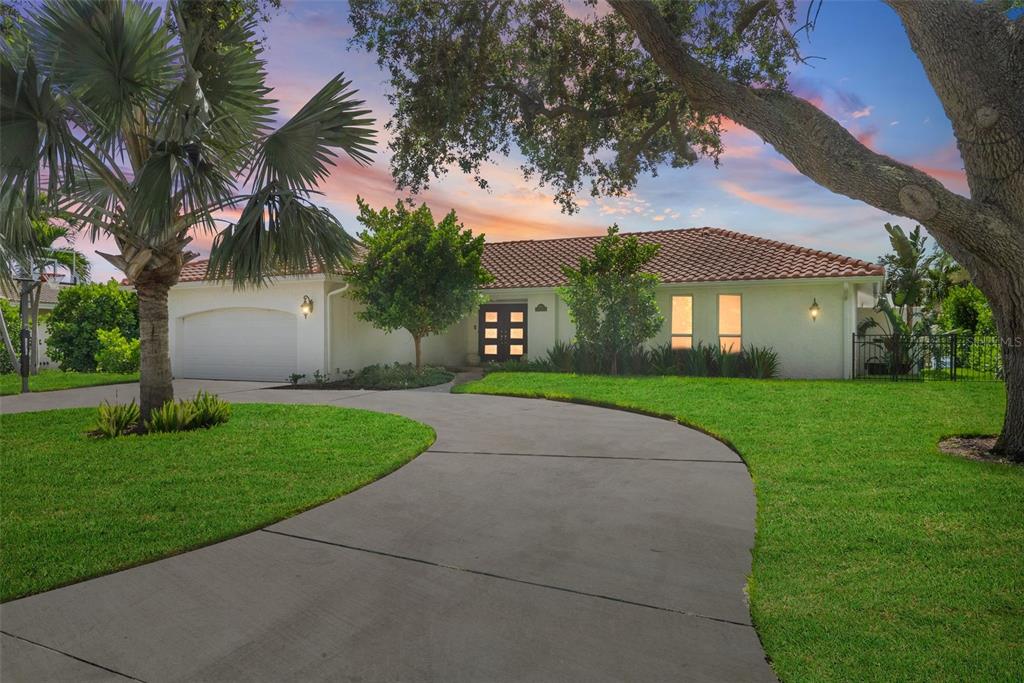 A single-story house with a tile roof, white exterior, and a curved concrete driveway — 1985 CAROLINA AVENUE NE, ST PETERSBURG, FL