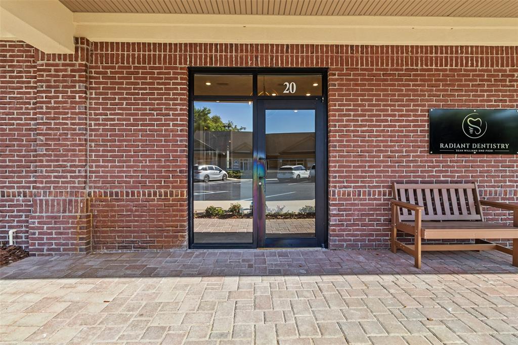 A brick building exterior features a glass door labeled 20 and a wooden bench — 13577 NW 2ND LANE UNIT 20, NEWBERRY, FL
