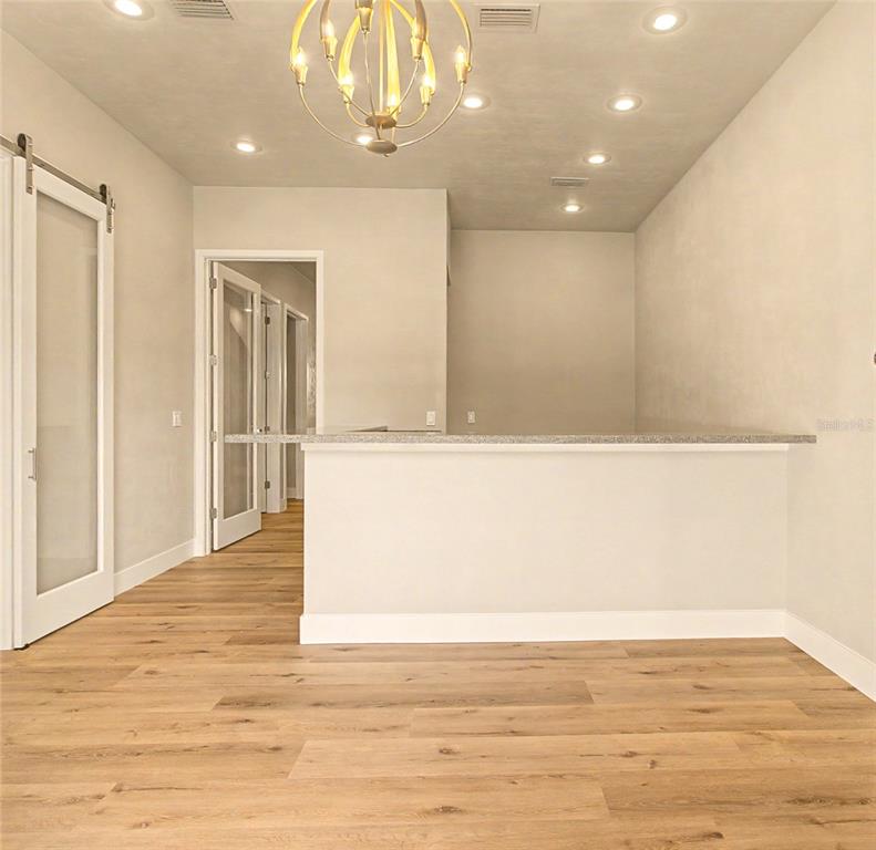 A room with light wood flooring, a breakfast bar, and a gold chandelier — 13577 NW 2ND LANE UNIT 20, NEWBERRY, FL
