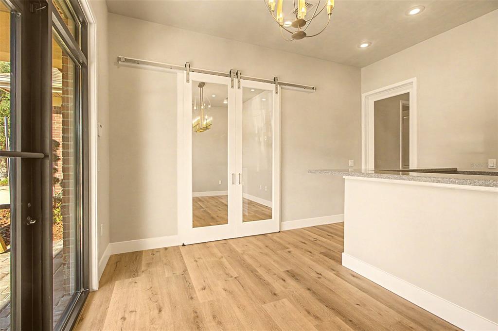 A room with light wood flooring, a granite-topped counter, and white sliding barn doors — 13577 NW 2ND LANE UNIT 20, NEWBERRY, FL