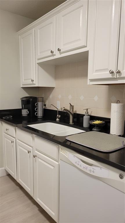 A kitchen features white cabinets, black countertops, a white sink, and a white dishwasher — 750 N TAMIAMI TRAIL UNIT 418, SARASOTA, FL