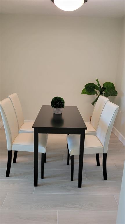 A dining area features a dark rectangular table, four white chairs, and a potted plant — 750 N TAMIAMI TRAIL UNIT 418, SARASOTA, FL
