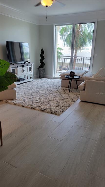 A living room features light wood-look tile flooring, a large area rug, and a balcony view — 750 N TAMIAMI TRAIL UNIT 418, SARASOTA, FL