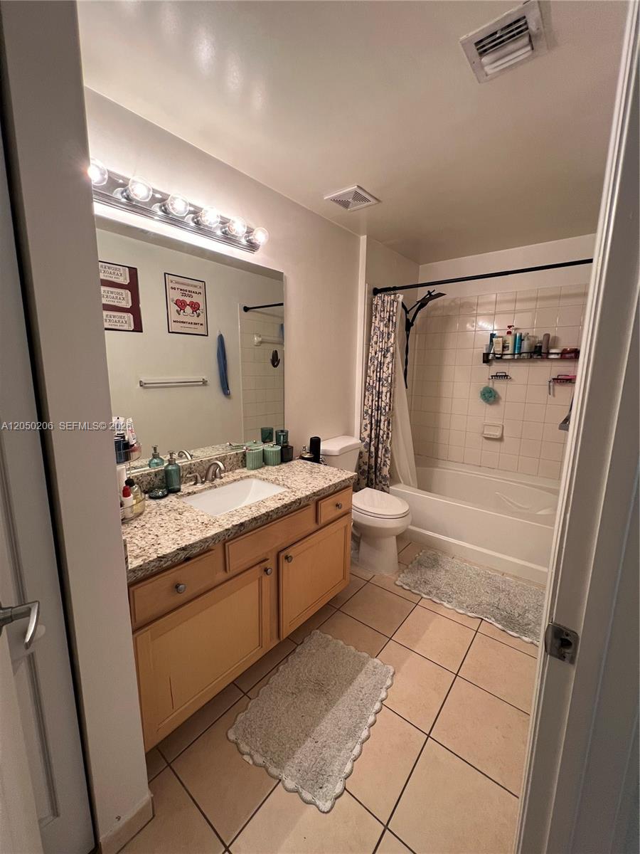 A bathroom features a granite vanity, light wood cabinets, a tiled shower-tub combo, and beige flooring — 6001 SW 70th St # 421, South Miami FL 33143, SOUTH MIAMI, FL