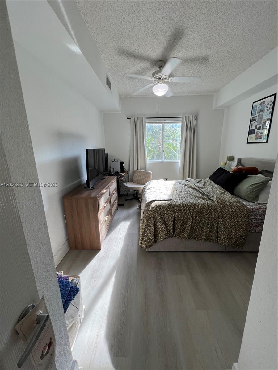 A bedroom features a bed, a wooden dresser with a television, and a ceiling fan — 6001 SW 70th St # 421, South Miami FL 33143, SOUTH MIAMI, FL