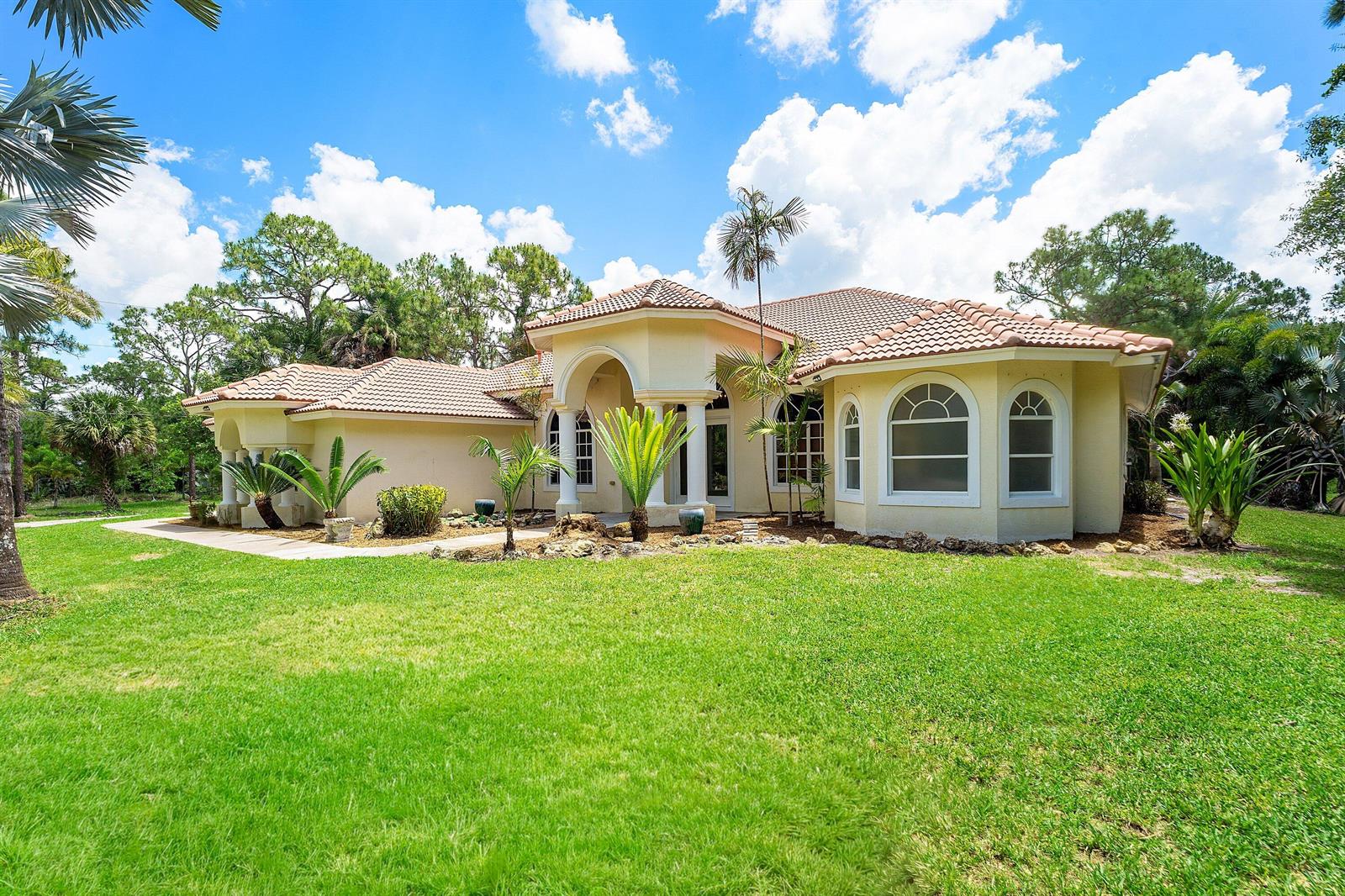 A single-story stucco house with a tile roof and arched windows sits on a lawn — 4956 200th Trail N, Loxahatchee FL 33470, LOXAHATCHEE, FL