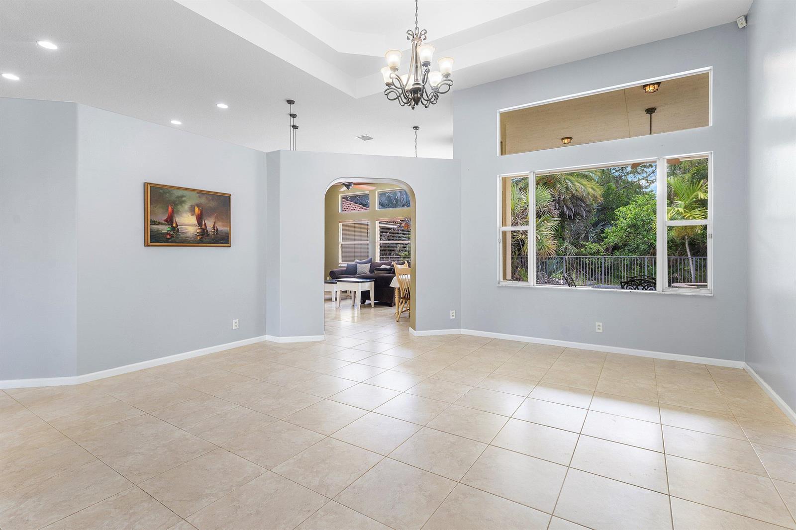 A spacious, light-gray living room features tile flooring, a tray ceiling, and a large window — 4956 200th Trail N, Loxahatchee FL 33470, LOXAHATCHEE, FL