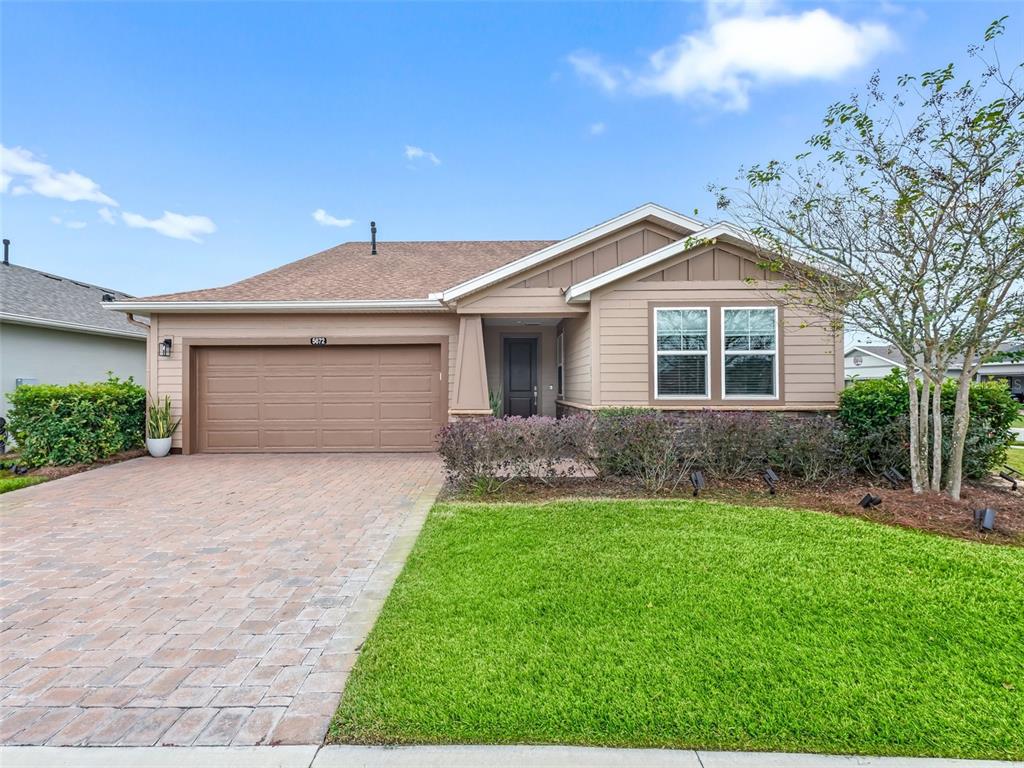 A single-story house with tan siding, a brick driveway, and a two-car garage — 5672 NW 40TH PLACE, OCALA, FL