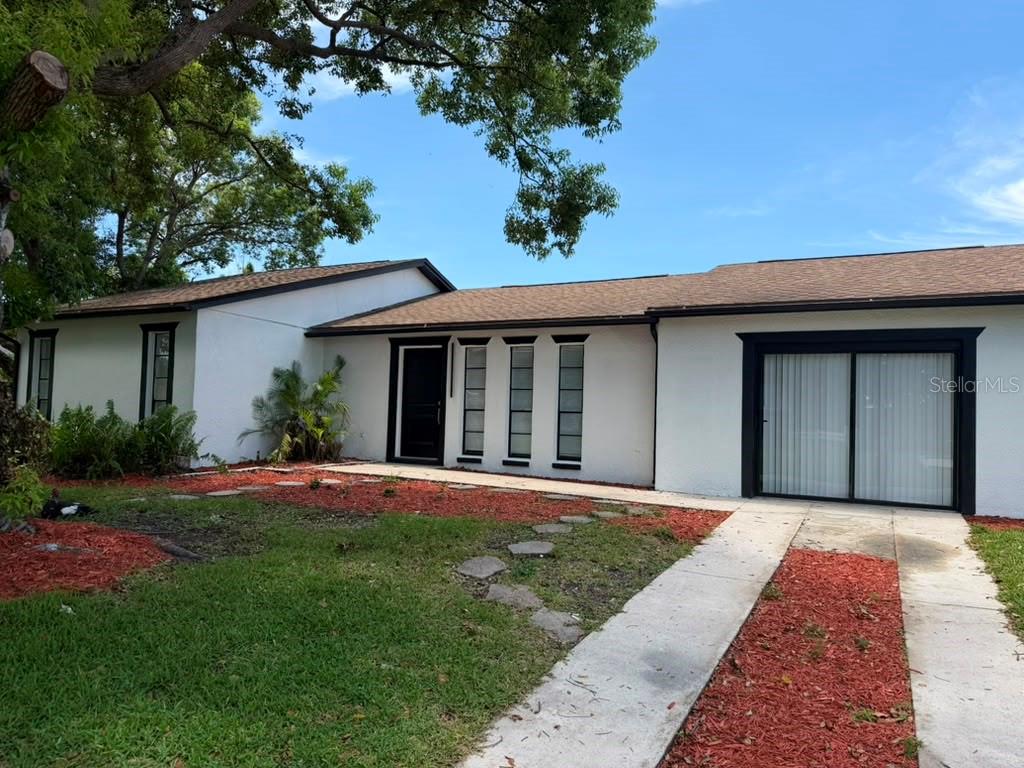 A single-story house with white stucco walls, black trim, and a brown shingled roof — 144 HIDALGO AVENUE, KISSIMMEE, FL