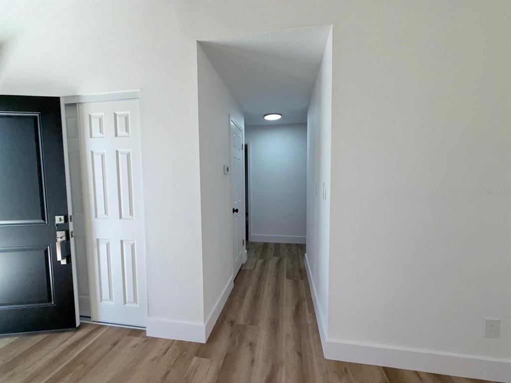 A hallway with light wood-look flooring leads to a doorway under a recessed ceiling light — 144 HIDALGO AVENUE, KISSIMMEE, FL