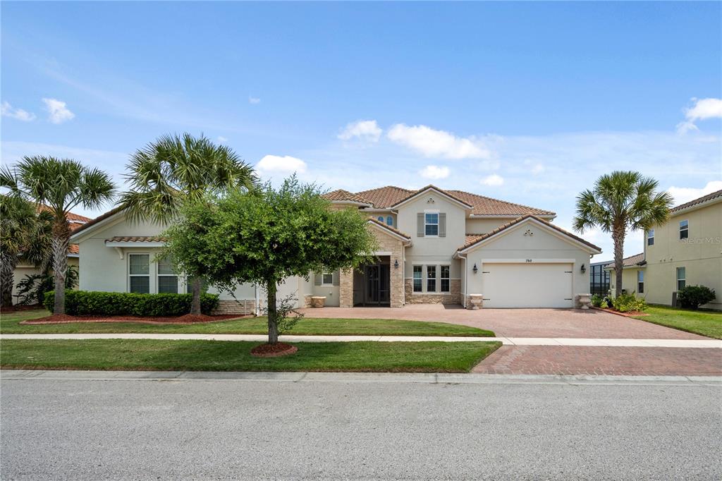 A two-story suburban house with a beige stucco exterior, stone accents, and a paved driveway — 760 WINDLASS COURT, KISSIMMEE, FL