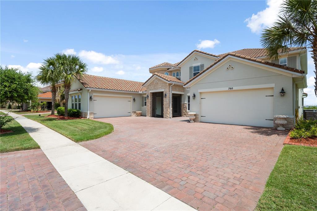A two-story house with a brick paver driveway, two garage doors, and a tiled roof — 760 WINDLASS COURT, KISSIMMEE, FL