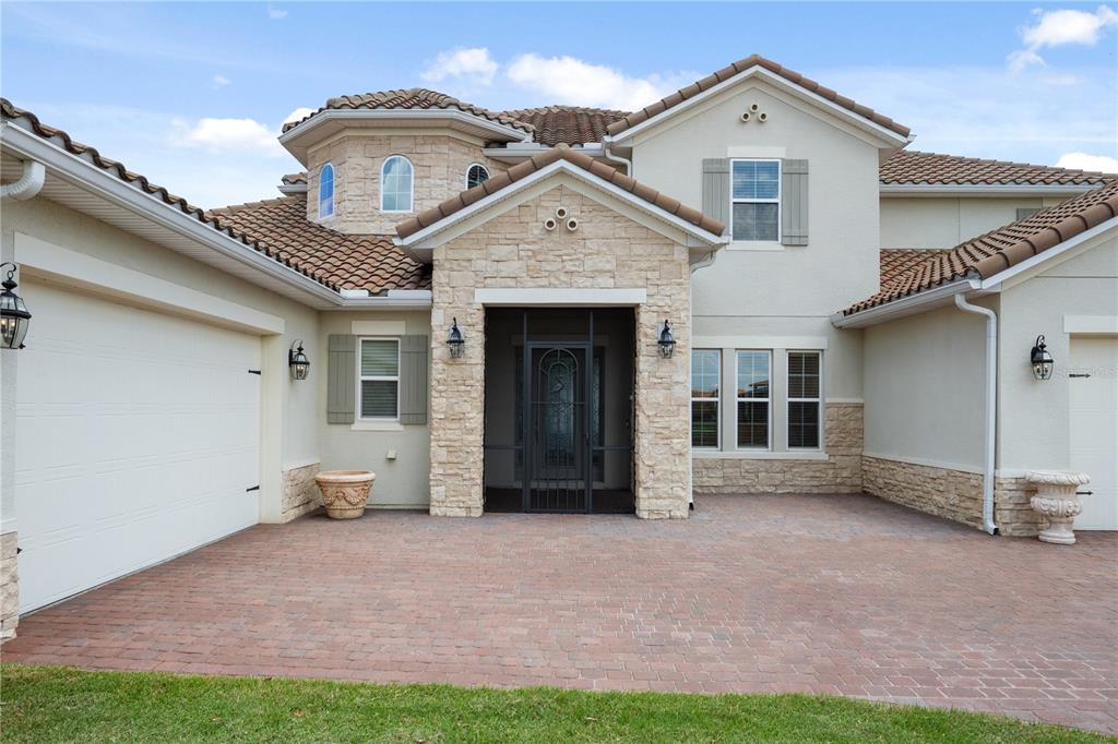 A two-story house exterior features a stone-accented entryway, a brick paver driveway, and a garage — 760 WINDLASS COURT, KISSIMMEE, FL