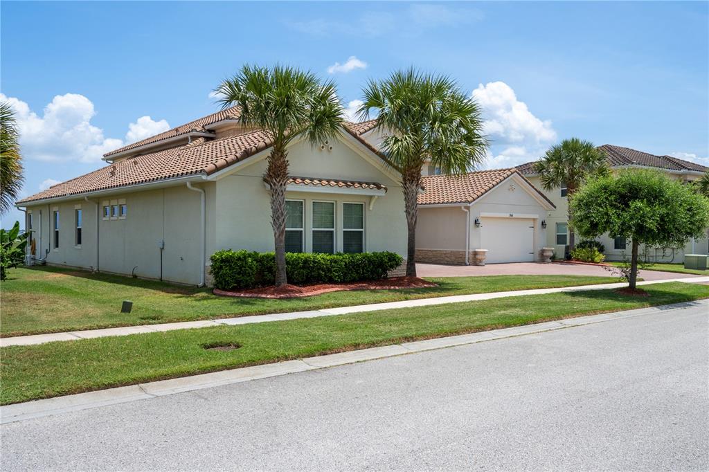 A beige single-story house with a tiled roof, two palm trees, and a paved driveway — 760 WINDLASS COURT, KISSIMMEE, FL