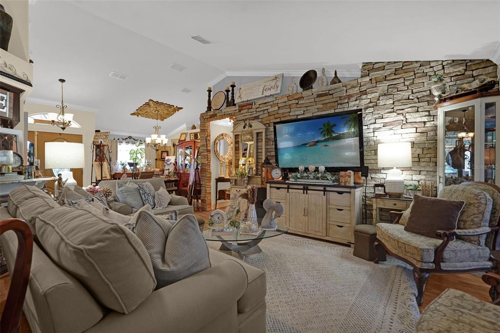A living room features a stone fireplace wall, a large television, and neutral-toned furniture — 3279 COUNTRYSIDE VIEW DRIVE, ST CLOUD, FL