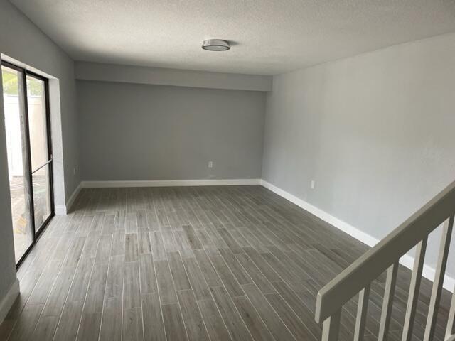 An empty room with gray walls, wood-look tile flooring, and a sliding glass door — 6905 69th Way, West Palm Beach FL 33407, WEST PALM BEACH, FL