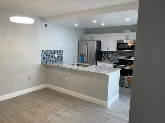 A kitchen with white cabinets, granite countertops, stainless steel appliances, and a tiled backsplash — 6905 69th Way, West Palm Beach FL 33407, WEST PALM BEACH, FL