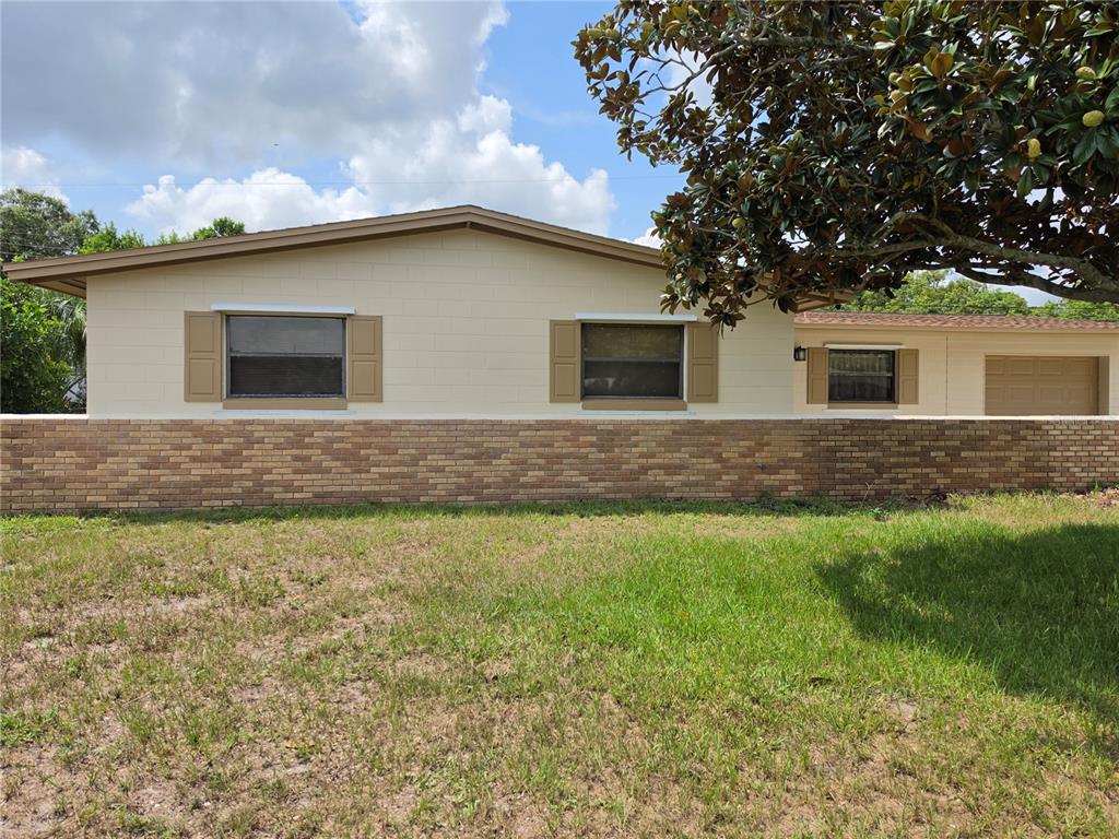 A single-story house with a brick base, beige block walls, and a garage — 969 ELKCAM BOULEVARD, COCOA, FL