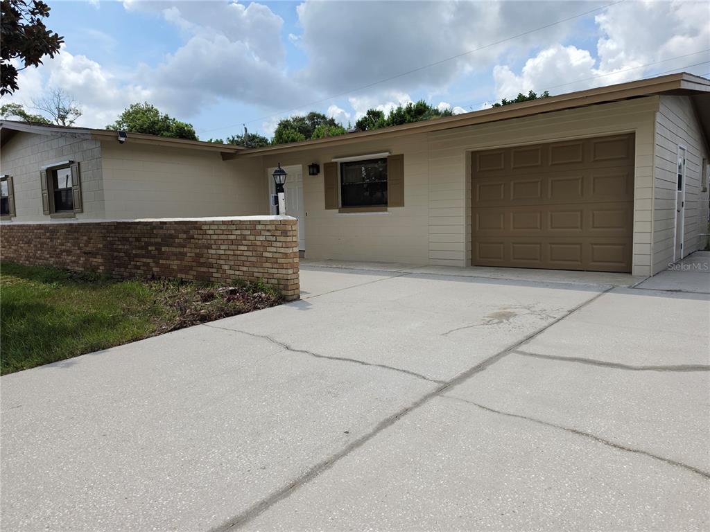 A single-story house with a beige exterior, a brick wall, and a brown garage door — 969 ELKCAM BOULEVARD, COCOA, FL