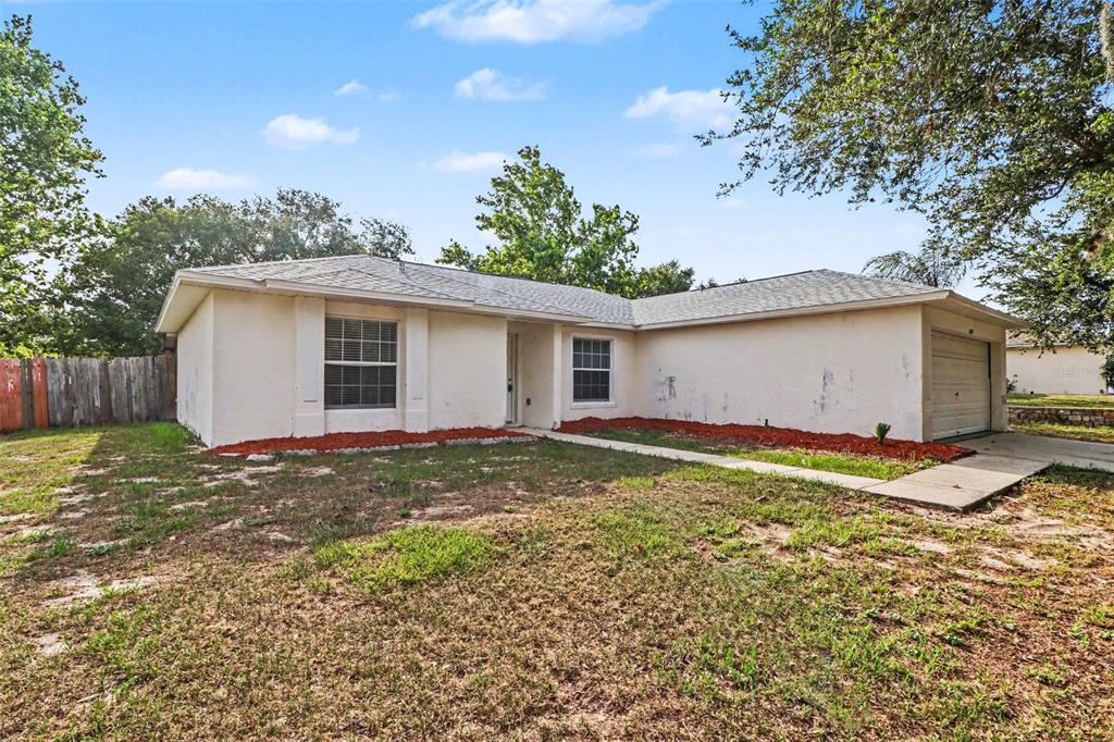 A single-story house with a white stucco exterior, a garage, and a front lawn — 10717 SIENA DRIVE, CLERMONT, FL